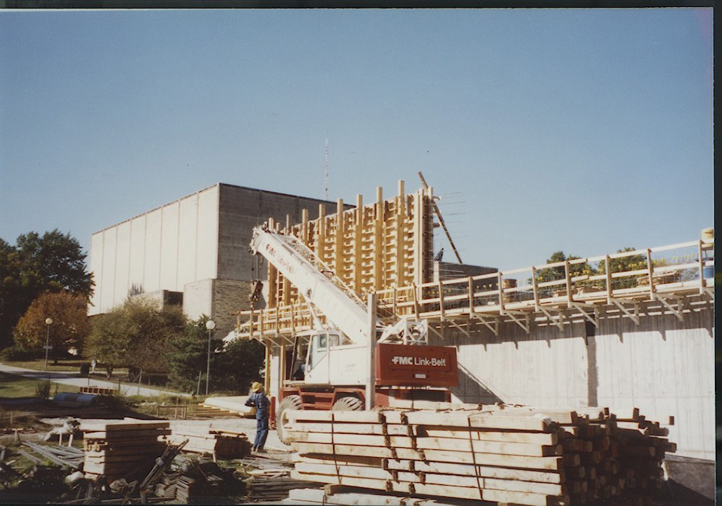 Photo of construction with wood forms to pour walls on the south side of the building.