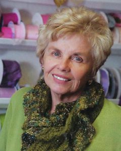 Lou Ann McKinnon Dunn smiling and standing in front of bolts of colorful ribbon used in her event business.