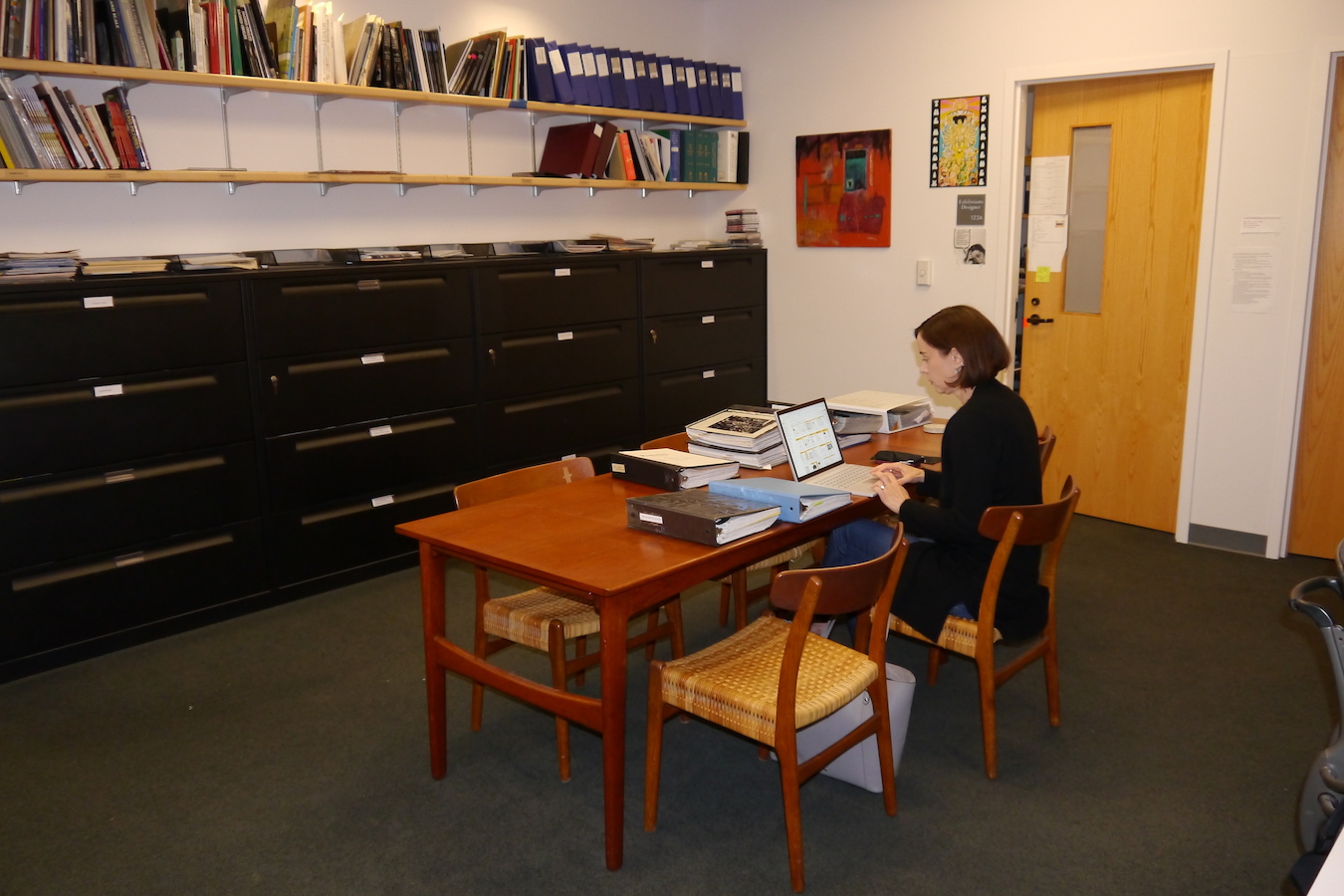 Visiting researcher sitting at desk with computer and utilizing the reference material.