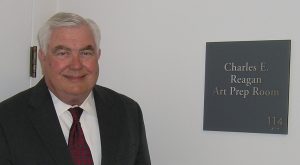 Charles “Chuck” Reagan beside the commemorative plaque by the Reagan art preparation area.