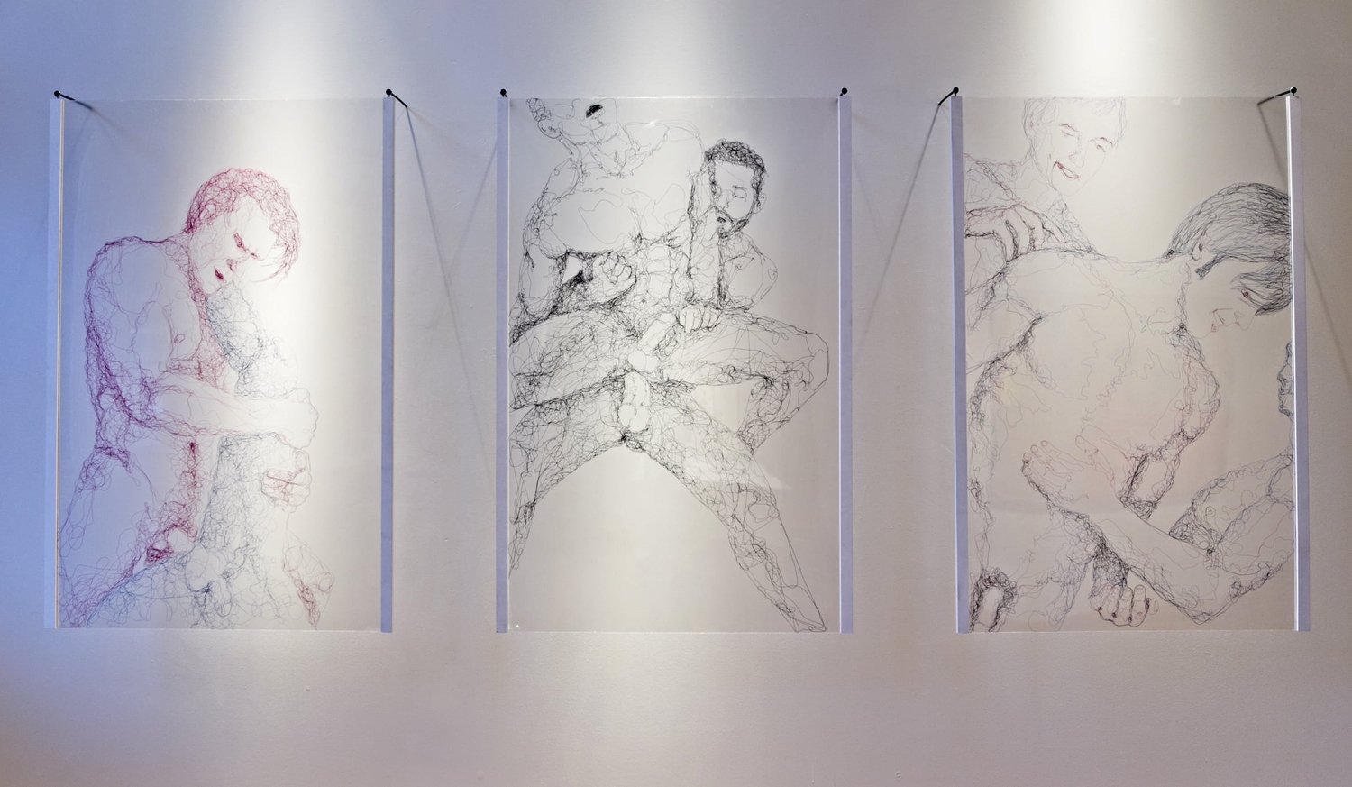 Three panels of thread art depicting nude males.