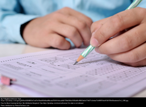 Picture of a kids hands writing notes on a sheet of paper.