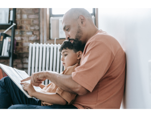 Male adult reading to male child on his lap