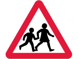 two schoolchildren crossing the street while holding hands on triangle with red boarder