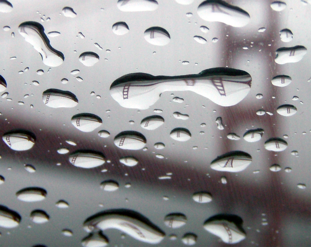 The Golden Gate Bridge refracted in rain drops acting as lenses on glass.