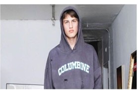 male model wearing a Bstroy Columbine hoodie; the hoodie has "bullet holes" in it.