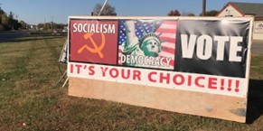 Political sign from Manhattan, Kansas. It reads, "Socialism, Democracy, Vote." Below those words are "It's Your Choice!!!"