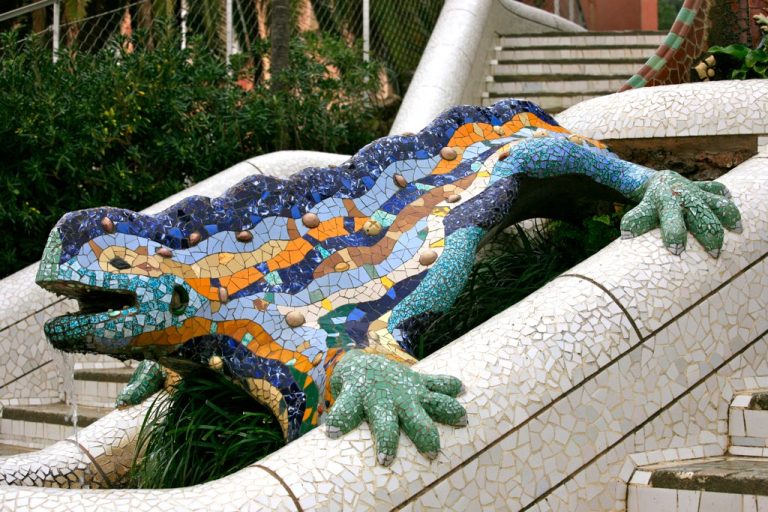 lagarto o dragón de mosaico colorido, con la boca abierta, bajando o vigilando una escalera de mosaico blanco